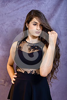 Portrait of a beautiful girl on a gray background, in a black dress with a serious look with perfect makeup isolated on black back