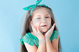 Portrait of a beautiful girl in a green dress on a blue background