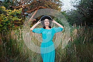 Portrait of a beautiful girl in a hat in a field in sunset light