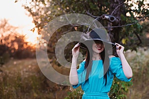 Portrait of a beautiful girl in a hat in a field in sunset light