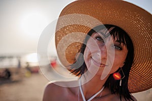 Portrait of a beautiful girl in a hat. Happy beautiful young woman smiling on the beach - Charming girl enjoying a sunny day -