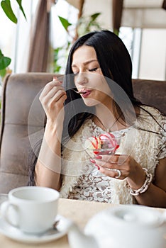 Portrait of beautiful girl having fun eating ice cream in coffee shop or restaurant, closeup