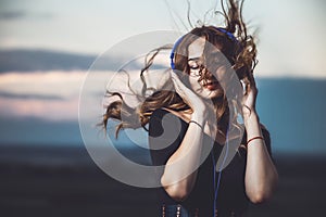 Portrait of a beautiful girl in headphones listening to music on nature