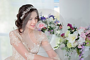 Portrait of beautiful girl in a luxurious wedding dress. Interior decorated with flowers