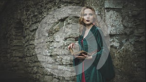 Portrait of a beautiful girl in the medieval green with a book