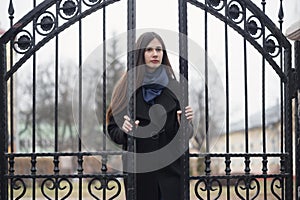 Portrait of a beautiful girl near the wrought-iron gate