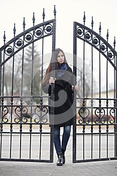 Portrait of a beautiful girl near the wrought-iron gate