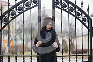 Portrait of a beautiful girl near the wrought-iron gate