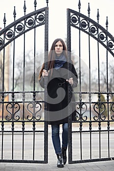 Portrait of a beautiful girl near the wrought-iron gate
