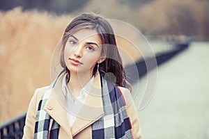 Portrait of a beautiful girl outside looking at you camera serious isolated defocused light brown background park outdoors