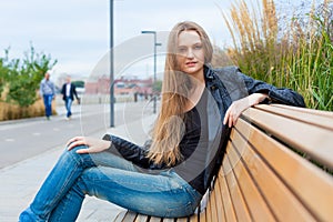 Portrait of a beautiful girl in the park on the bench. Close up