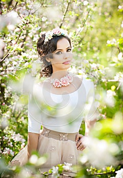Portrait of beautiful girl posing outdoor with flowers of the cherry trees in blossom during a bright spring day
