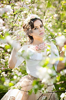 Portrait of beautiful girl posing outdoor with flowers of the cherry trees in blossom during a bright spring day