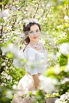 Portrait of beautiful girl posing outdoor with flowers of the cherry trees in blossom during a bright spring day