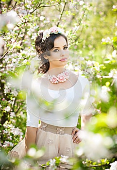 Portrait of beautiful girl posing outdoor with flowers of the cherry trees in blossom during a bright spring day