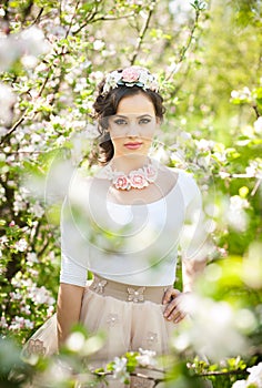 Portrait of beautiful girl posing outdoor with flowers of the cherry trees in blossom during a bright spring day