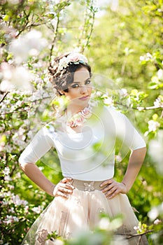 Portrait of beautiful girl posing outdoor with flowers of the cherry trees in blossom during a bright spring day