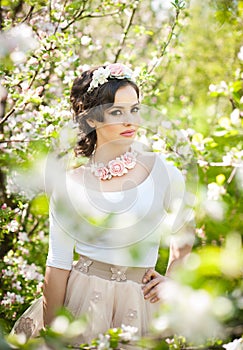 Portrait of beautiful girl posing outdoor with flowers of the cherry trees in blossom during a bright spring day