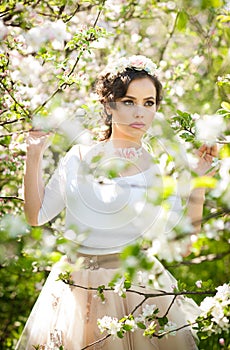 Portrait of beautiful girl posing outdoor with flowers of the cherry trees in blossom during a bright spring day