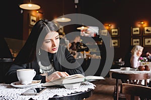 Portrait of a beautiful girl reading book in cafe