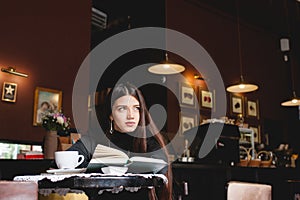 Portrait of a beautiful girl reading book in cafe