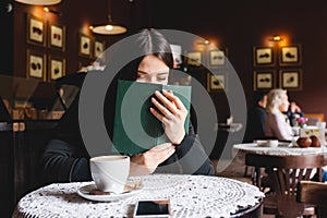 Portrait of a beautiful girl reading book in cafe