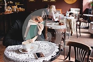 Portrait of a beautiful girl reading book in cafe