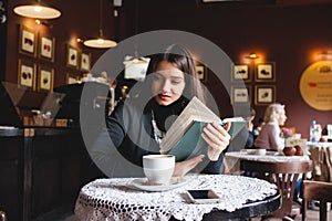 Portrait of a beautiful girl reading book in cafe