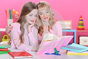 Portrait of beautiful girl reading book with mother