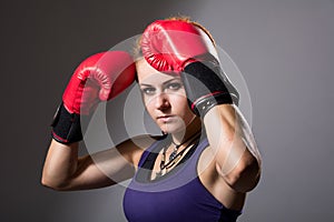 Portrait of beautiful girl with red boxing gloves, aggressive an