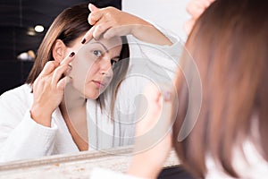 Portrait of a beautiful girl, in the reflection of the mirror. Fingers remove acne on the face