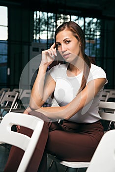 Portrait of a beautiful girl sitting on a chair in a white T-shirt