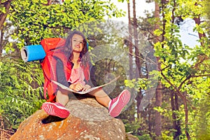 Girl with map sit on stone during hike