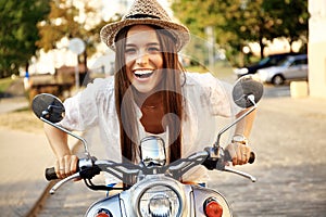 Portrait of a beautiful girl sitting on silver retro scooter, smiling and looking at the camera