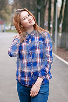 Portrait of a beautiful girl. smiling, posing on camera. in a blue shirt in a cage. Against the background of the autumn