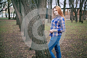 Portrait of a beautiful girl. smiling, posing on camera. in a blue shirt in a cage. Against the background of the autumn