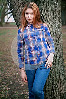 Portrait of a beautiful girl. smiling, posing on camera. in a blue shirt in a cage. Against the background of the autumn