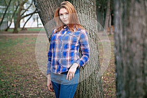 Portrait of a beautiful girl. smiling, posing on camera. in a blue shirt in a cage. Against the background of the autumn