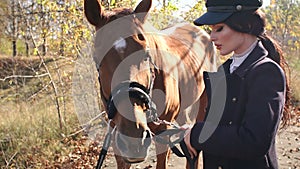 Portrait of beautiful girl in special clothes and hat with brown horse in autumn