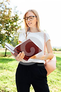 Portrait of a beautiful girl student with glasses reading a book