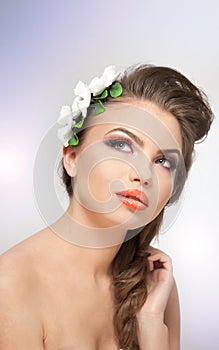 Portrait of beautiful girl in studio with white flowers arrangement in her hair and naked shoulders. young woman