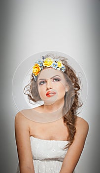 Portrait of beautiful girl in studio with yellow roses in her hair and naked shoulders. young woman with professional makeup