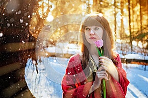 Portrait of a beautiful girl on a Sunny day in the spring forest, which holds a delicate Tulip. Bright warm Sunny day