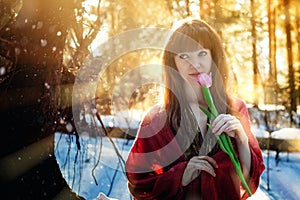 Portrait of a beautiful girl on a Sunny day in the spring forest, which holds a delicate Tulip. Bright warm Sunny day