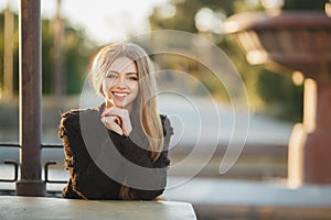 Portrait of a beautiful girl at a table in the street cafe