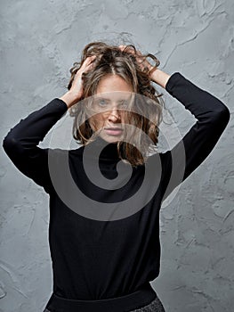 Portrait of beautiful girl touching with both hands her wild messy hair