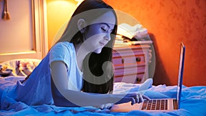 Portrait of beautiful girl typing message on laptop at night