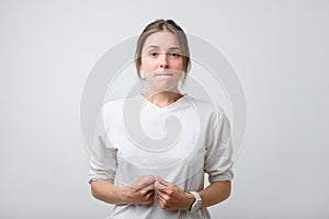 Portrait of beautiful girl in white t-shirt frowning her face in displeasure, keeping arms folded.