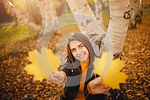 Portrait of beautiful girl in yellow sweater in autumn forest with maple leaves