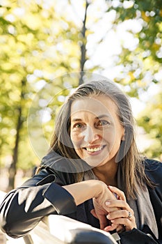 Portrait of  beautiful gray-haired elderly woman in  park on  bench